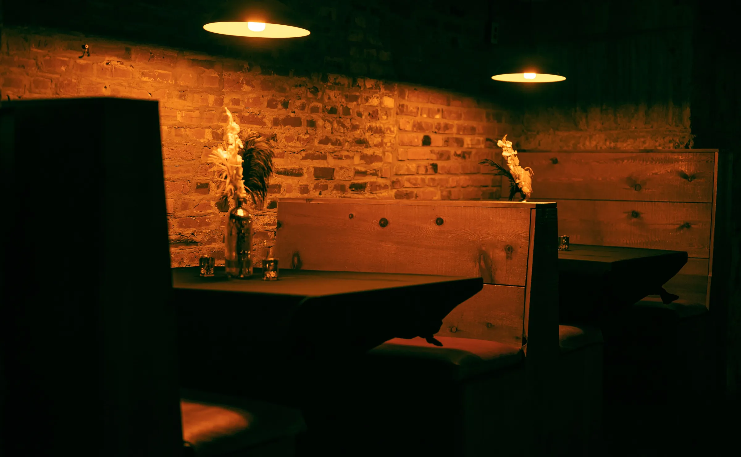 A candlelit wooden booth against a brick wall