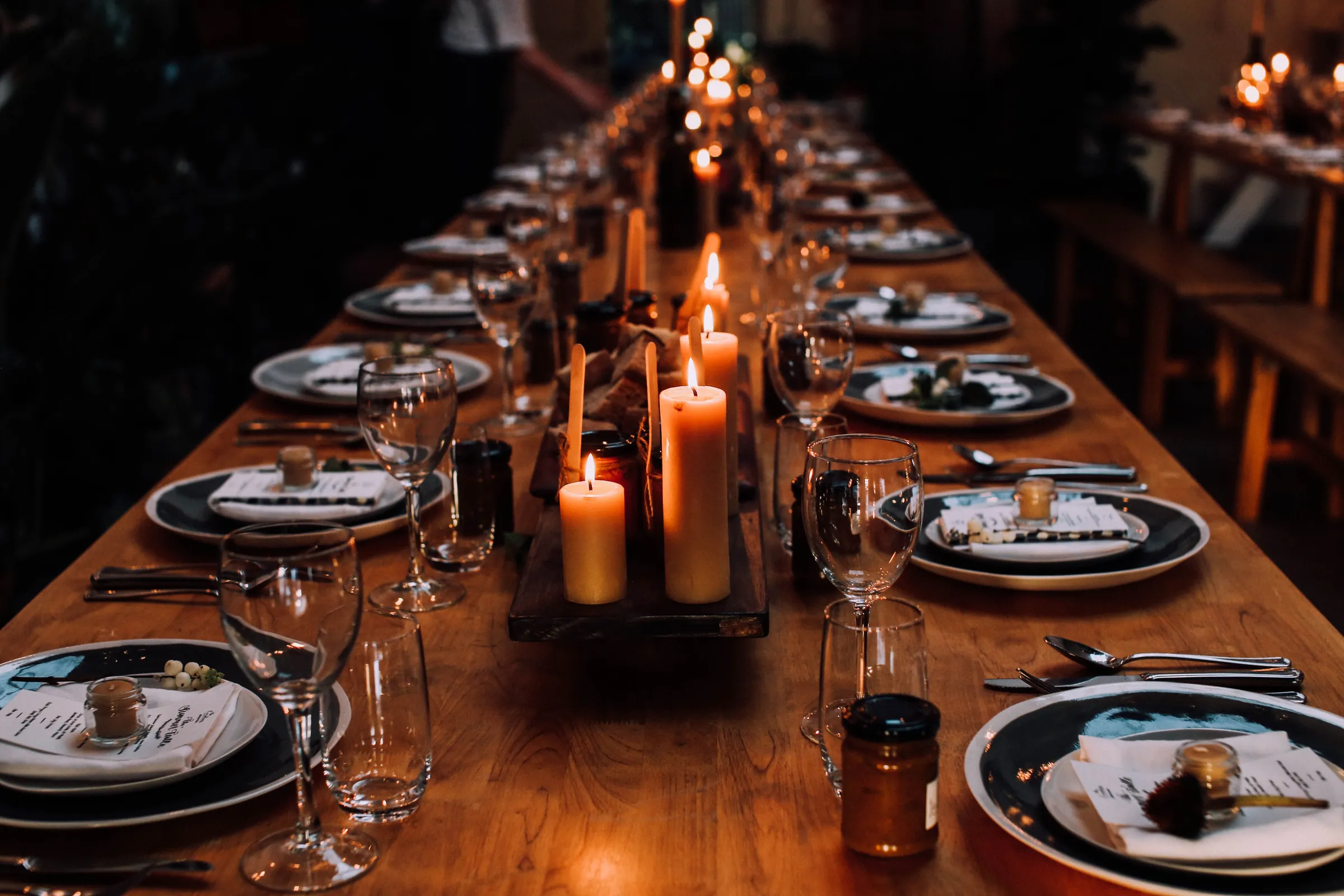 A long wooden table laid for a feast with candles down the middle